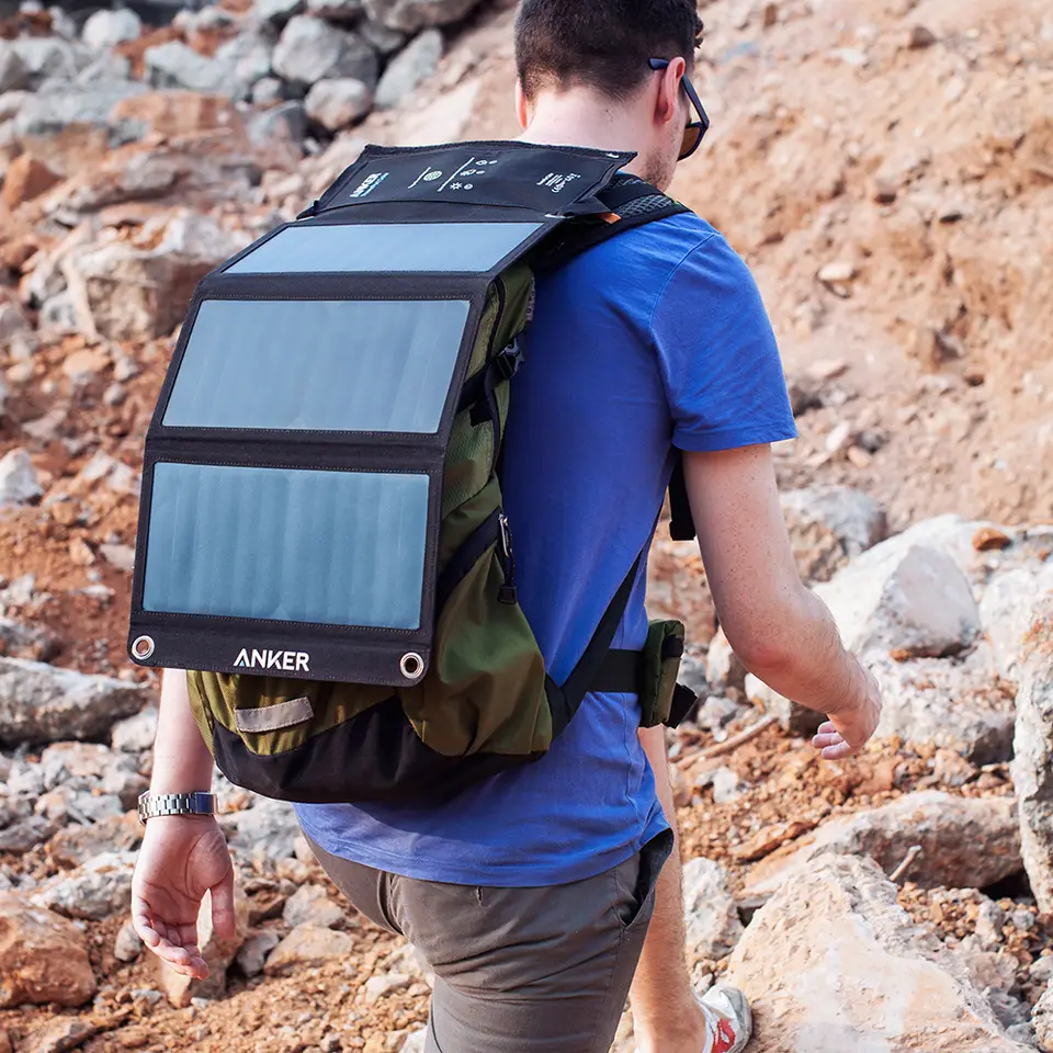 Une personne en randonnée avec un chargeur solaire Anker PowerPort Solar 21W attaché à son sac à dos.